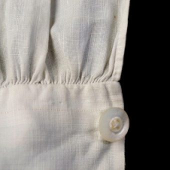 Near the edge of the cuff, a single thread has been drawn from the linen fabric to mark a straight line and to ensure that the pieces are square to the grain.